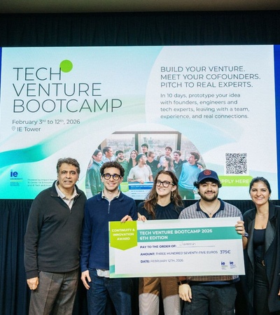 A group of people at a Tech Venture Bootcamp event showcasing their project and prize.