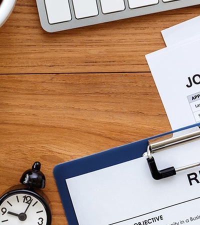 A workspace featuring a job application and resume alongside a cup of coffee and a clock.