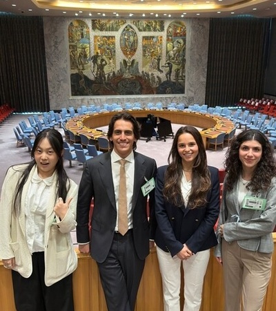 A group of four people poses in front of the UN Security Council chamber.