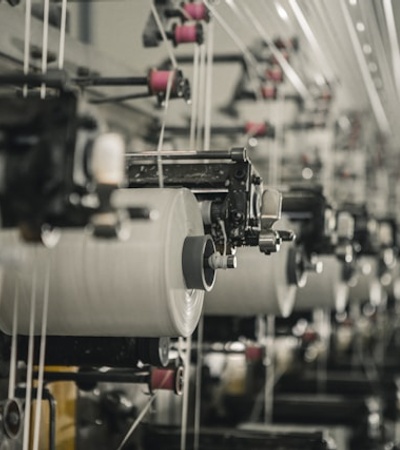 An image showing a row of textile machines spinning yarn in an industrial setting.