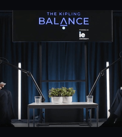 A conversation between two men sitting in modern chairs in a studio setting.
