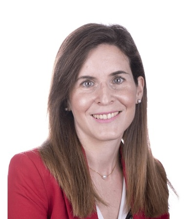A smiling woman wearing a red blazer and white top against a plain white background.