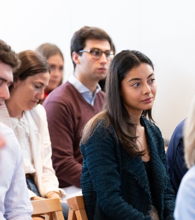 A group of people sitting in a row, attentively listening in a seminar or class.