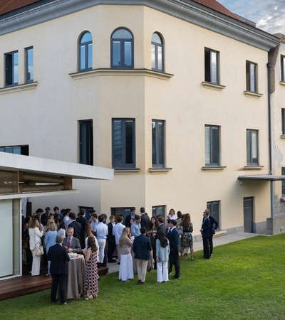 A group of people gathered outside a modern house for an event.