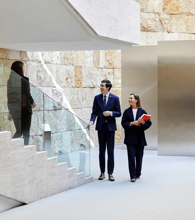 People in a modern corporate building interior, featuring a sleek design with marble and minimalist elements.