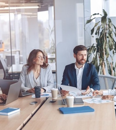 A group of professionals are engaged in a meeting around a table in a modern office.