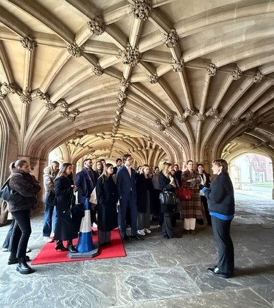 A group of people gathered for a tour in a historic architectural space with ornate ceilings.