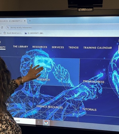 A person is interacting with a large digital screen displaying a university library portal with various resource options.