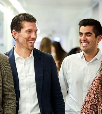 A group of four people laughing and walking together in a corridor.