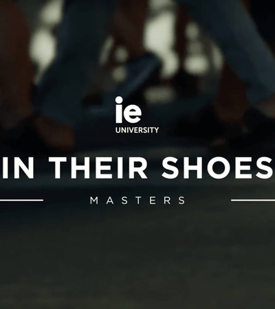 A promotional image featuring a close-up view of people's feet in shoes, with the text 'IE University' and 'IN THEIR SHOES - Masters' overlaid.