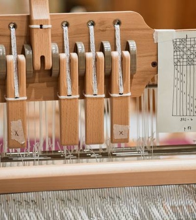 Close-up view of a loom showing detailed parts such as levers and a weaving pattern instruction sheet.