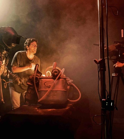A scene depicting two individuals working on a creative project with smoke and lighting effects.