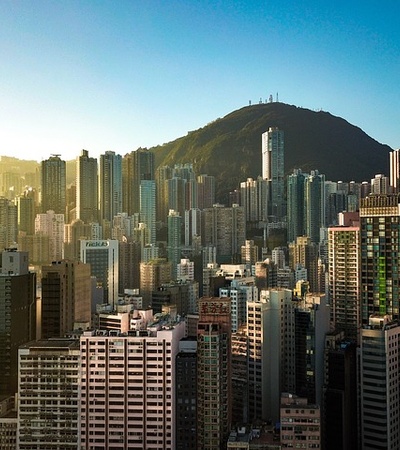 A cityscape showing numerous high-rise buildings with a mountain in the background during sunset.