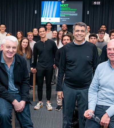 A group of people posing for a photo in a classroom setting with a presentation screen in the background.