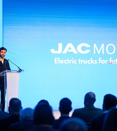 A speaker presenting about electric trucks at a JAC Motors event.