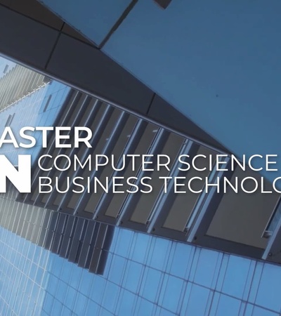 An advertisement for a Master in Computer Science & Business Technology displayed on a modern building.