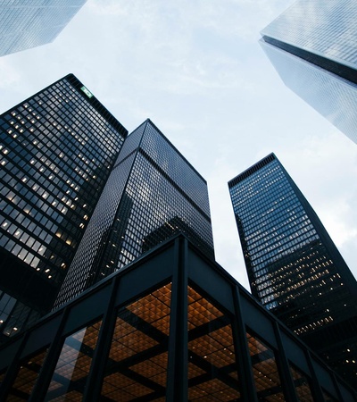 A view looking up at tall skyscrapers under a cloudy sky.