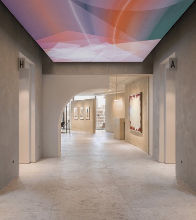 A modern art gallery hallway with colorful ceiling lights and artwork displayed on the walls.