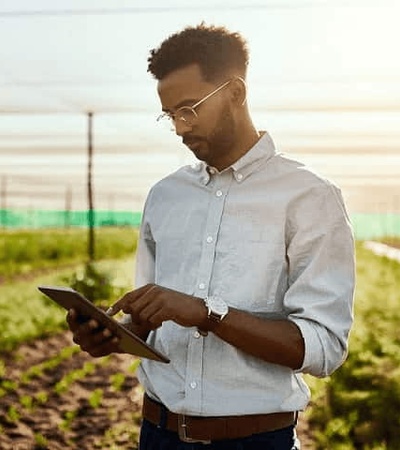A man using a tablet in a field during sunset.