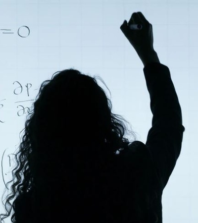 A silhouette of a person writing mathematical equations on a clear board.