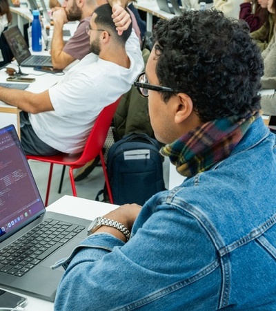 A group of students working on their laptops in a classroom setting.