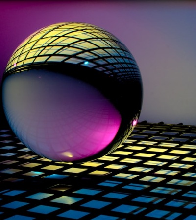 A reflective sphere resting on a grid with colorful lighting effects.