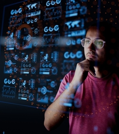 A person looks thoughtfully at digital data and graphs displayed on a transparent screen.