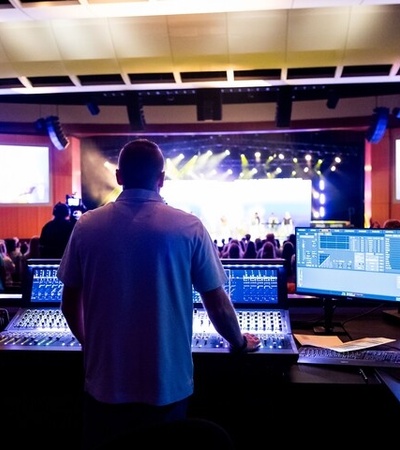 A sound engineer is operating equipment in front of a live audience during a performance.