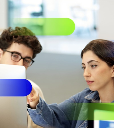 A woman points at a computer screen while a man observes her attentively.