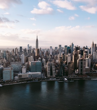 A panoramic view of a vibrant city skyline with a river in the foreground.