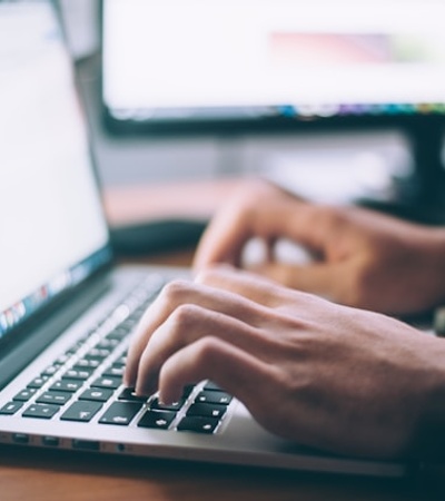 A person's hands typing on a laptop keyboard.