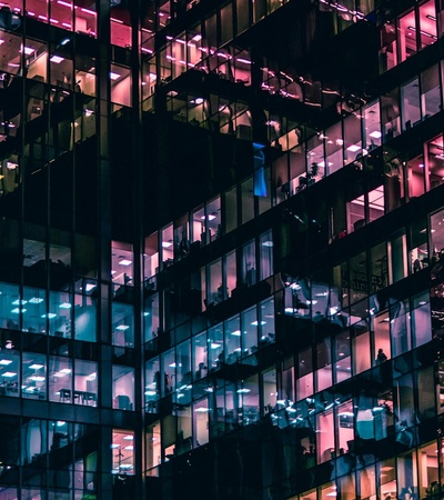 A modern office building illuminated with colorful lights at night.