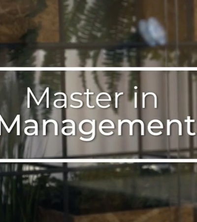 Sign reading 'Master in Management' displayed in a window, with reflections of plants and building interiors.