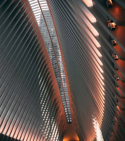 An interior view of a modern architectural structure featuring a high ceiling with symmetrical ribbed design and ambient lighting.