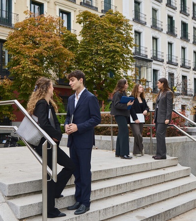 A group of professionally dressed individuals conversing and networking in an urban park setting.