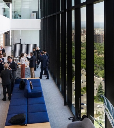 Business professionals gathered on a modern office building balcony overlooking a cityscape.