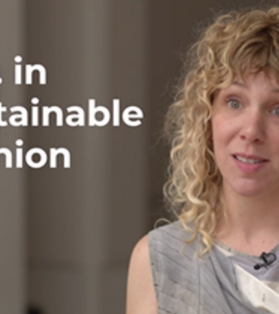 A woman with curly hair discussing the Master of Science in Sustainable Fashion program.