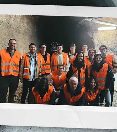A group of people wearing safety vests posing inside a tunnel.