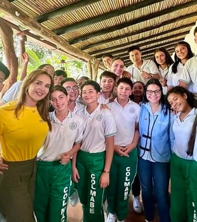 A group of students and adults smiling together in a natural setting.