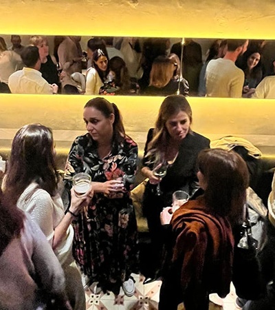 A lively social gathering with people conversing and enjoying drinks in a well-lit bar.