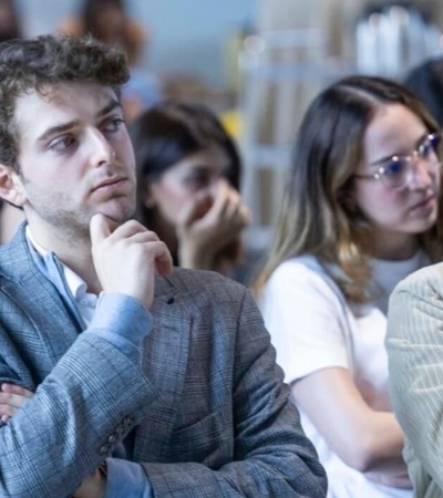 A group of young adults attentively listening at a conference or seminar.