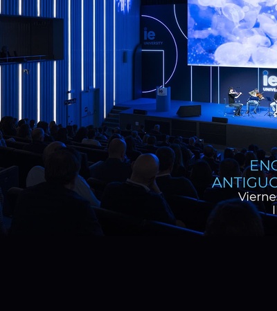 An event for alumni taking place in a modern auditorium with blue lighting.