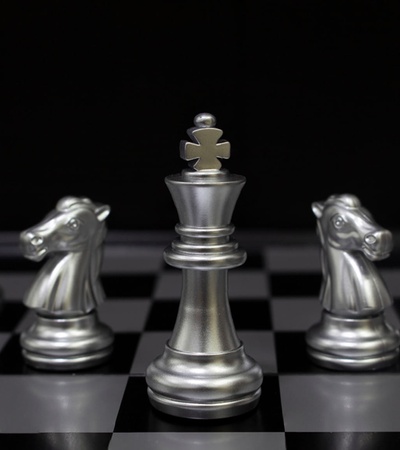 A close-up of silver chess pieces on a black chessboard.