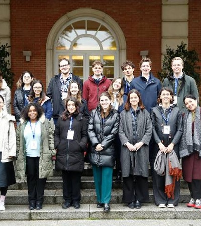 A diverse group of people posing together on steps in front of a building.