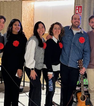 A group of seven people wearing red flower pins, standing together in a casual setting.
