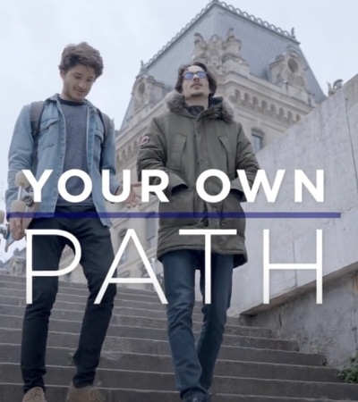 Two young men walking down the stairs with a historical building in the background and the phrase 'YOUR OWN PATH' overlaid.