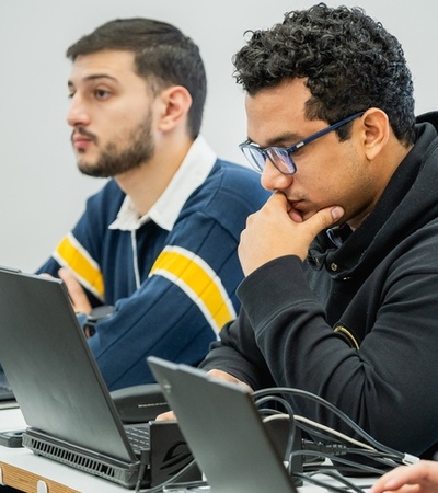 Two students engaged in a classroom setting with laptops.