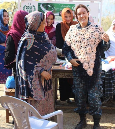 A group of women gathered outdoors, celebrating and showcasing handmade crafts.