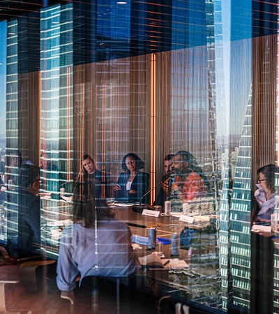 A meeting taking place in a modern office with a cityscape reflection in the windows.