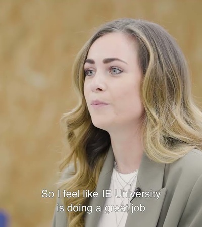 A woman is speaking positively about her university experience in a classroom setting.